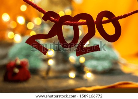 new year sign silhouette in bokeh lights. Text 2020. Christmas card in orange background 