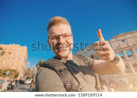 Happy man tourist with backpack with glasses taking selfie photo Colosseum in Rome, Italy.