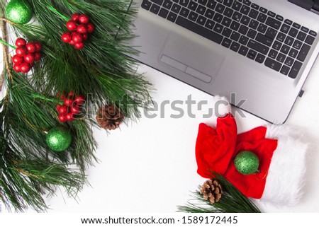Office white table with computer, pine branch and santa hat. Christmas background. Copy space. Top view.