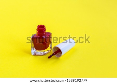 red nail polish on yellow background. bottle of nail polish