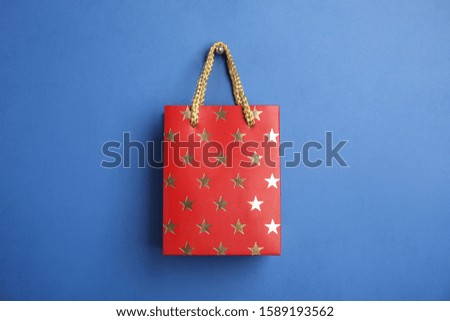 Red shopping paper bag with star pattern on blue background