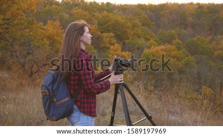 Girl traveler with camera takes beautiful photos of nature. Young independent female tourist photographer, photographs a beautiful autumn landscape with professional digital camera. travel concept
