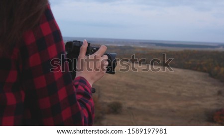 Girl traveler with camera takes beautiful photos of nature. Young independent female tourist photographer, photographs a beautiful autumn landscape with professional digital camera. travel concept