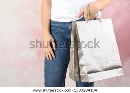 Woman with silver shopping paper bags on pink background, closeup