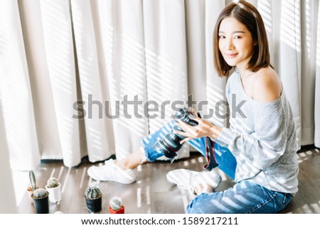 Portrait of young beautiful Asian girl photographer taking picture object shots of cactus on the floor in room studio and looking at camera. Happy Blogger and freelance working online marketing. SME.