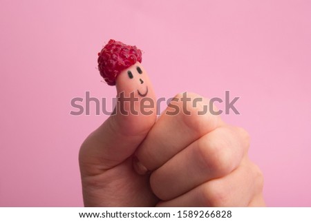 Funny fingers faces in hat raspberries berry against pink background. Happy family couple healthy eating concept.