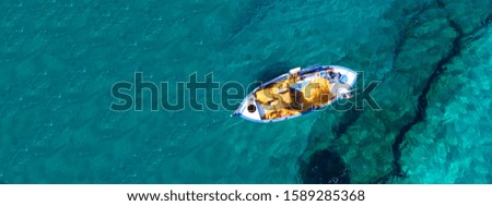 Aerial drone top down ultra wide photo of traditional fishing boat docked in world famous paradise beach of Mykonos island, Cyclades, Greece