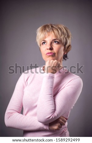 Woman with short blond hair thinking or dreaming. People and emotions concept