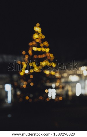 A vertical picture of a Christmas tree with blurry lights during the nighttime