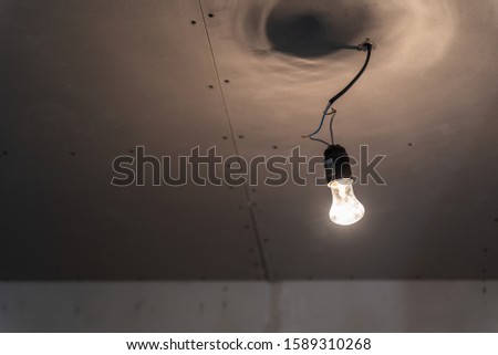 Pendant lamps in loft style against rough wall with gray cement plaster. Edison light bulbs.