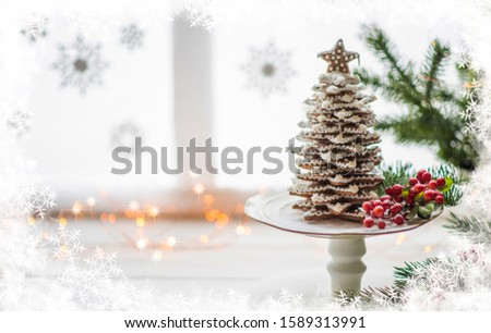 The handmade eatable gingerbread and New Year Tree with decoration. Gingerbread over defocused magic light winter window. Wonderful holiday mood. Copy space for your text.