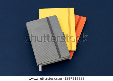 Stationery set next to multi-colored notebooks on the blue background.
