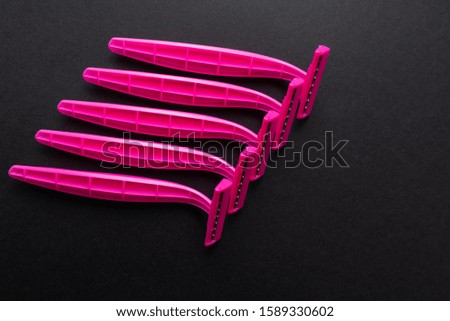 pink female razor on black background