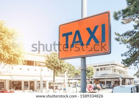 taxi service sign hanging on pole in metal frame at city street outdoors