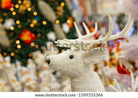Christmas background picture decorative white deer toy on bright Christmas tree lights winter holidays background  