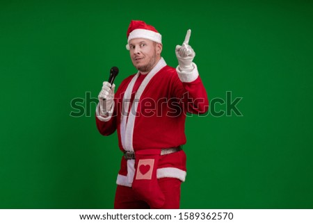 Emotional Santa Claus holds a microphone in his hands, sings and poses on a green background