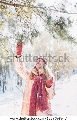 A vertical shot of a blonde female in enjoying the winter miracle during the snowflake in a forest
