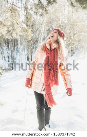 A vertical shot of a blonde female in enjoying the winter miracle during the snowflake in a forest