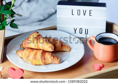 Breakfast in bed. Croissants with jam and coffee. Lightbox with the inscription Love you.