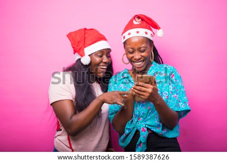 young black African women wearing Xmas hat standing on a pink background excited