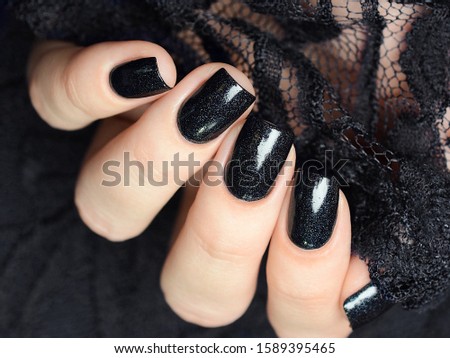 dark blue manicure with a shimmer against a background of black lace