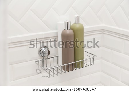 Toiletries bottles on suction cups compact bath shelf, fixing on tiled wall without drilling Royalty-Free Stock Photo #1589408347