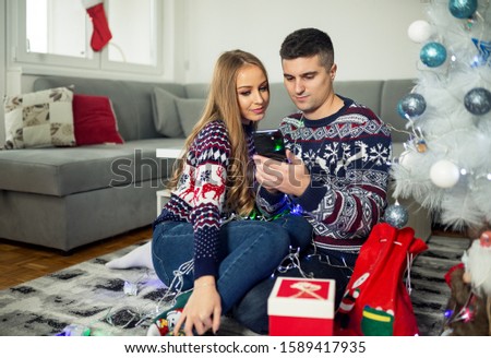 Couple in New Year sweater using phone at home