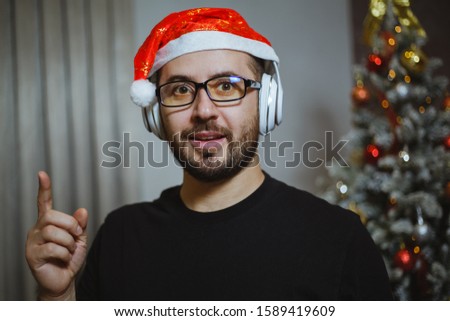 Portrait of a man with a cap like Santa Claus and listening to music in headphones. Christmas atmosphere.