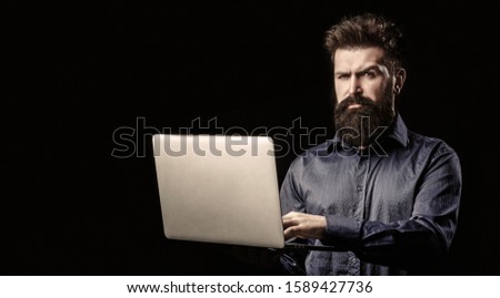 Businessman using his laptop, pc. Serious handsome bearded man worker laptop. Bearded male businessman holding a computer in his hands isolated on black background. Copy space.