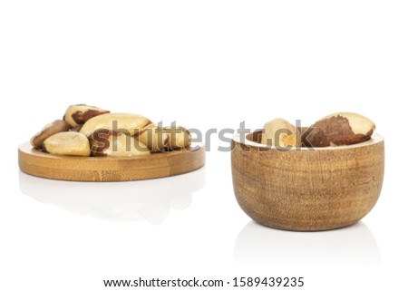Lot of whole brazil brown nut in bamboo bowl on round bamboo coaster isolated on white background