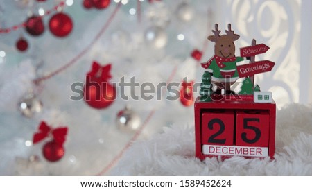 Merry Christmas. Holiday's decorations, sweets and wooden cube calendar with 25 december day under pine tree branch.Against the background of white spruce.