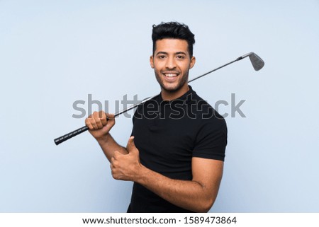 Handsome young man playing golf over isolated blue background with thumbs up because something good has happened