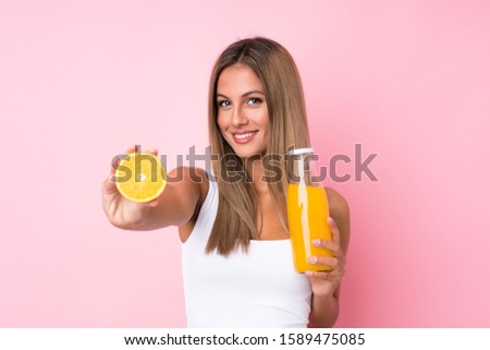 Young blonde woman over isolated background holding an orange