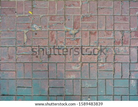 Grunge cracked red street tiles with blue paint. City street pavement cobblestone pattern. Urban civil footpath floor tiles