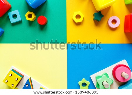 Wooden kids toys on colorful paper. Educational toys blocks, pyramid. Toys for kindergarten, preschool or daycare. Copy space for text. Top view	