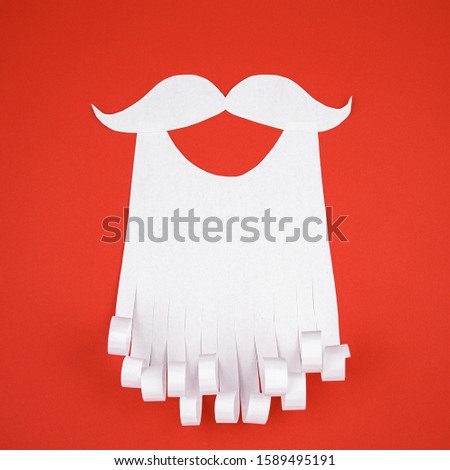 White paper beard on a red background. The concept of Christmas and New Year holidays.