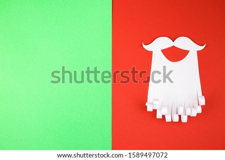 White paper beard on red and green background. The concept of Christmas and New Year holidays.