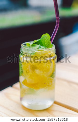 lemonade cocktail garnished with lemon and mint On Table. non alcoholic drink in vintage mason jar glass. lemon drink in glass with metal straw, natural eco friendly reusable, zero waste lifestyle.