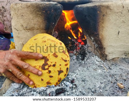 In this picture the rotis are being cooked on the fire and the bread is almost cooked.