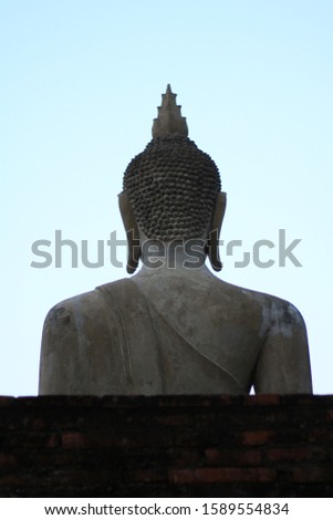 Backside of the Buddha statue with light blue sky background.  Pay homage to the Buddha in Ayutthaya, Thailand. The Buddha statue at Wat Yai Chai Mongkhon or the Great Monastery of Auspicious Victory.