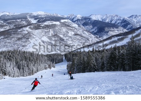 People alpine downhill skiing on trail at Vail ski resort in the Colorado Rocky Mountains in winter