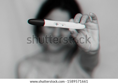 positive pregnancy test in hands of happy pregnant girl close up. Black and white monochrome photography with 3D glitch effect