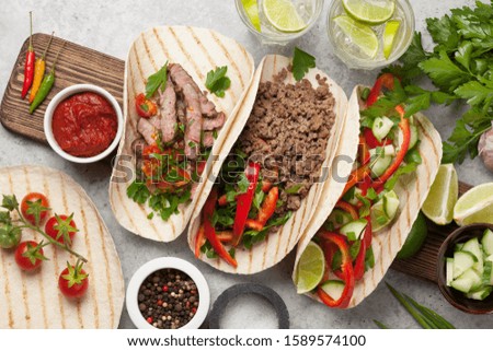 Set of mexican tacos with meat and vegetables in tortilla. And caipirinha cocktail. Top view on stone table. Flat lay