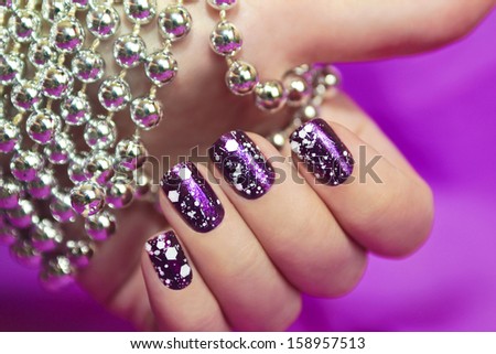 Snow manicure with the design of the white crumbs on violet brilliant varnish for the nails. Royalty-Free Stock Photo #158957513
