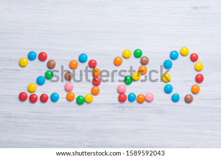 on a light gray background, colorful sweet jelly beans are laid out in the form of the next year.