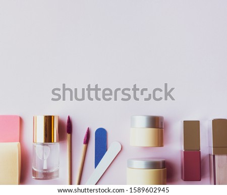 Assorted cosmetic products, moisturizer, cream, lipstick, nail files, lip gloss and sponges on pastel background. Beauty concept. Flat lay design.