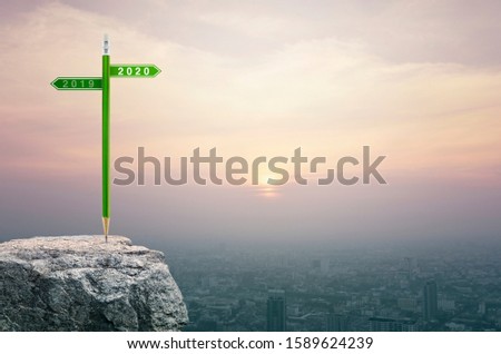 2020 and 2019 direction sign plate with green pencil on rock mountain over aerial view of cityscape at sunset, vintage style, Business strategy planning concept, Happy new year 2020 calendar cover