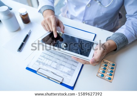 Doctor reading on a document report and writing on paperwork and searching treatment information at office, Medical healthcare concept