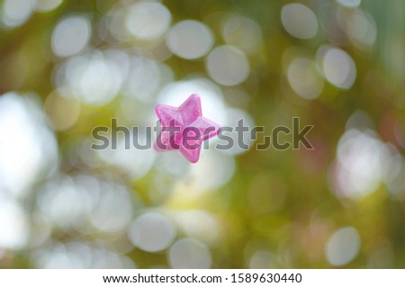 Plastic pink star shape over blur background.