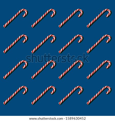 Pattern of hard candy cane striped in Christmas colors on classic blue background. Red and white striped hard candy cane. Christmas background. 